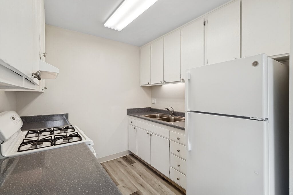 A white kitchen leading into the dining room at Canyon Rim Apartments in San Diego, California.